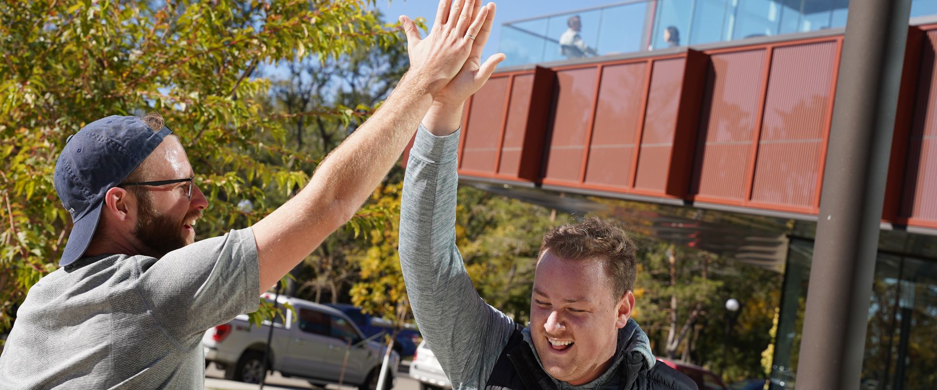 Two males outside Cultivator headquarters smiling and giving each other a high five.