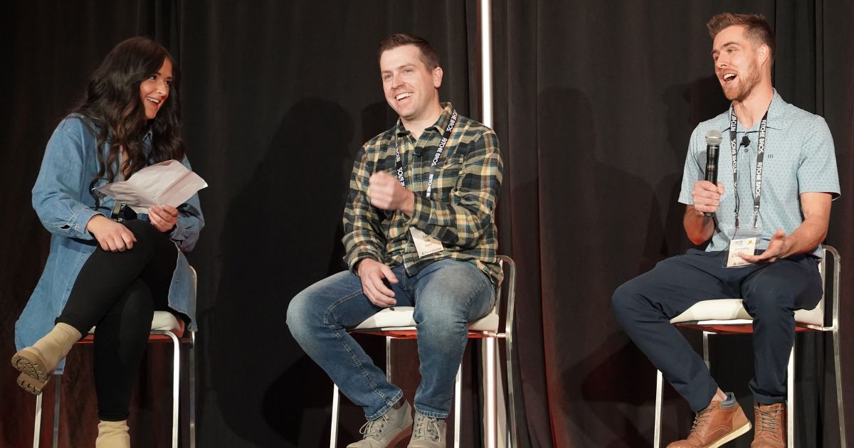 Ami Caragata, Kyle Folk, and Brady Fahlman, sit on high stools on the Grain Expo stage.