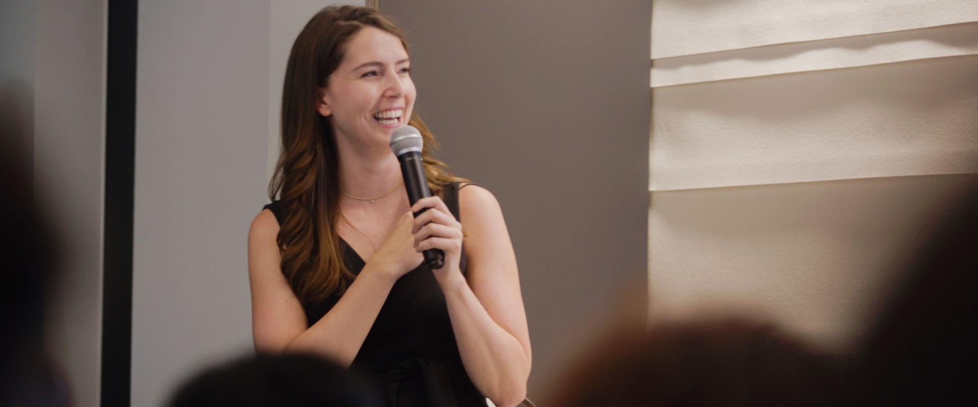 Twello CEO, Kayla Baum, stands in front of a crowd smiling while holding a mic. 