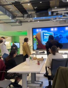 Wide shot of the Pitch Space nine monitor wall at Cultivator with people looking at the trivia question presentation.