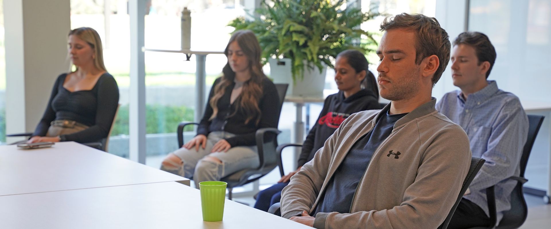 Five Cultivator company team members taking part in mindfulness session by sitting in chairs with eyes closed.