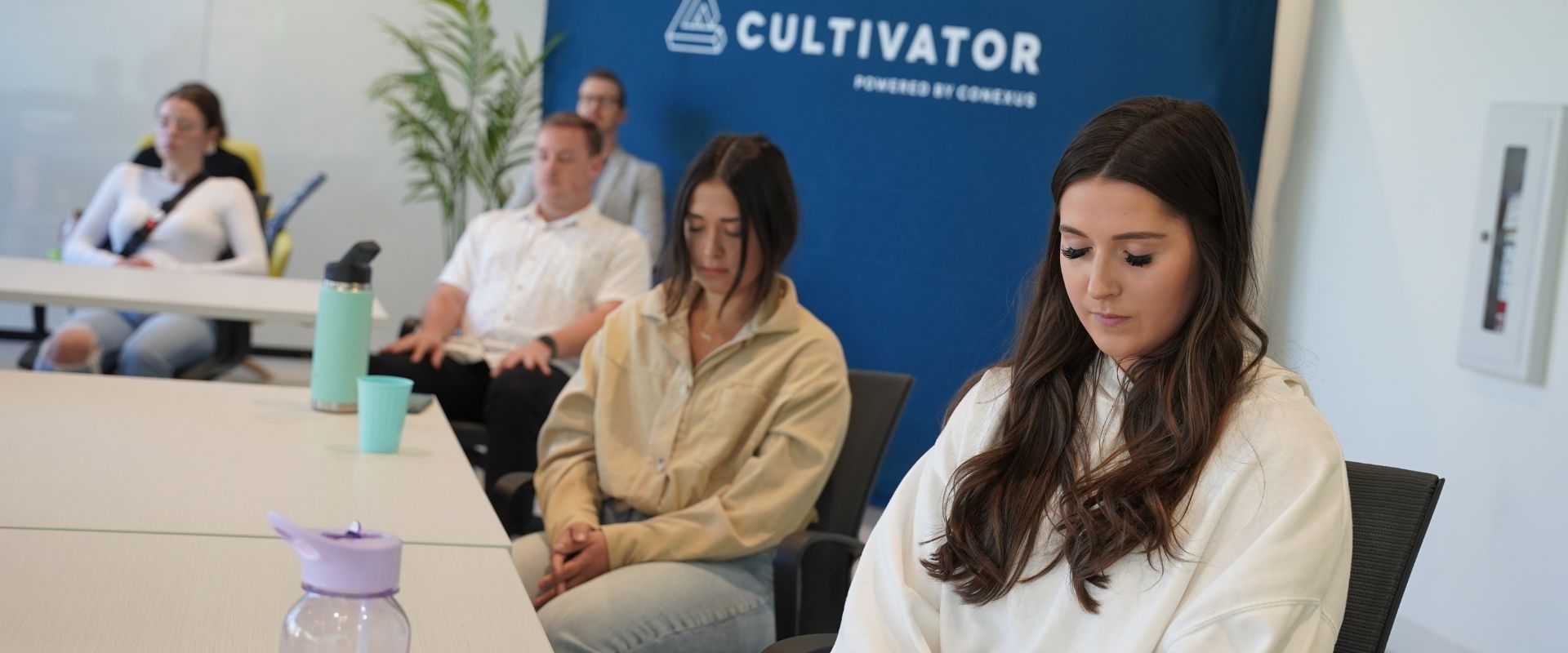 Five Cultivator company team members sitting with eyes closed and heads down as they meditate.