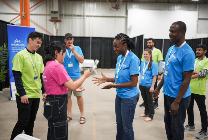 Participants playing rock paper scissors in colourful t-shirts