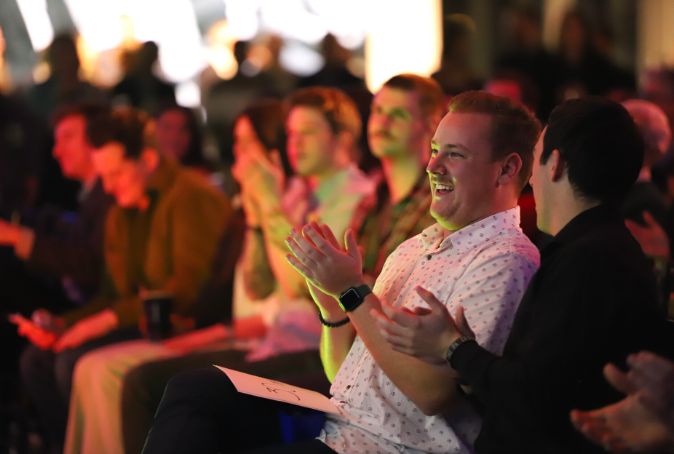 Group of people sitting and clapping, with focus on two individuals.