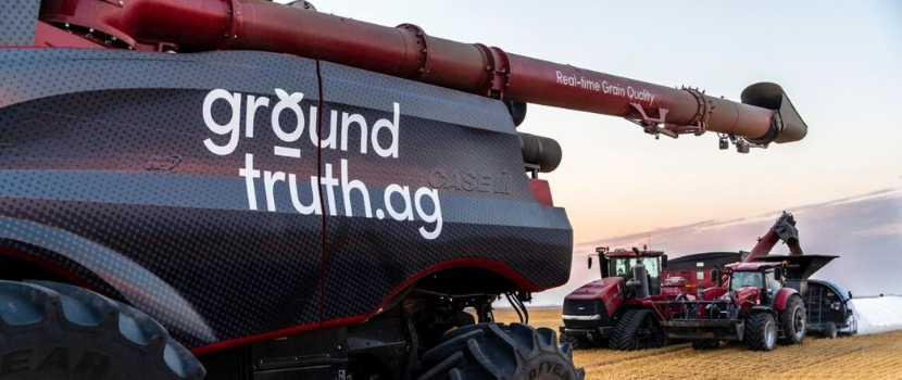A combine in a field with the words, Ground Truth Ag, on the side