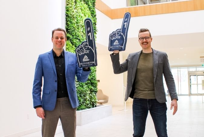 Andrew Doen and Jordan McFarlen pose for a picture waving Cultivator foam fingers