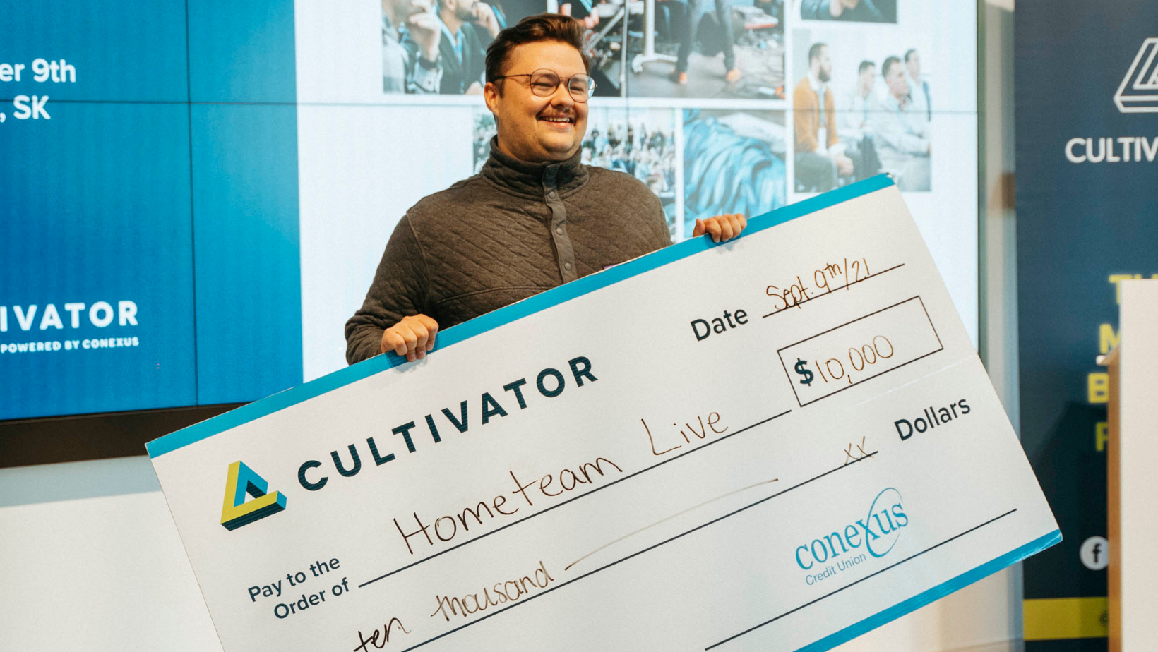 Tanner Goetz, founder of HomeTeam Live, smiling with $10,000 cheque