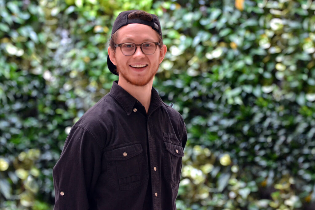 Sam Dietrich, Co-founder of Prairie Robotics Standing in front of a living wall