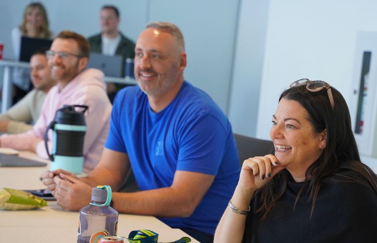 Cultivator Founders sit at table smiling as they listen to a guest speaker.
