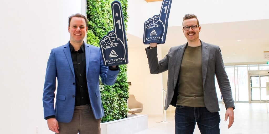 Andrew Doen and Jordan McFarlen pose for a picture waving Cultivator foam fingers