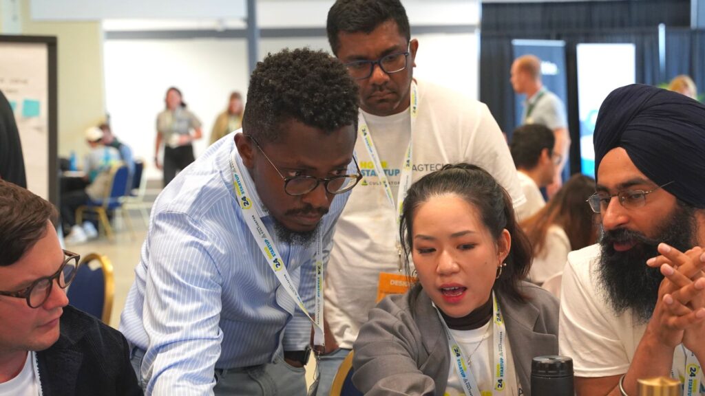 Four people surround a computer while collaborating on new innovation idea