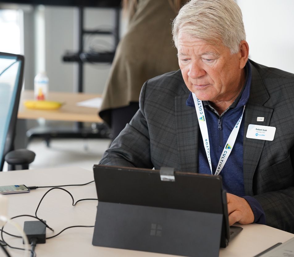 Rob Saik types on his computer wearing a Cultivator lanyard.