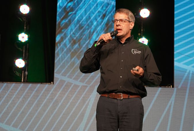 Rob Hannam, CEO of Farm Health Guardian, talks into microphone while pitching at Canada's Farm Show