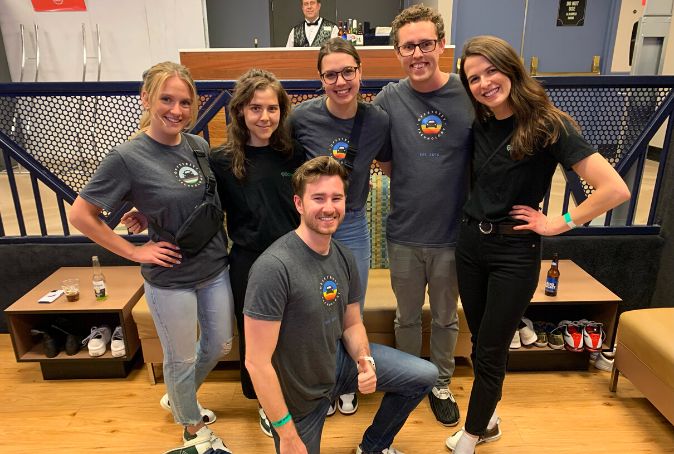 A team of 6 people pose for a photo at a bowling alley.